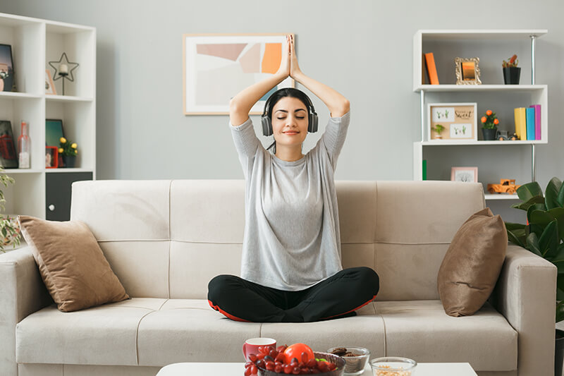 A photo of a young girl wearing headphones doing yoga sitting