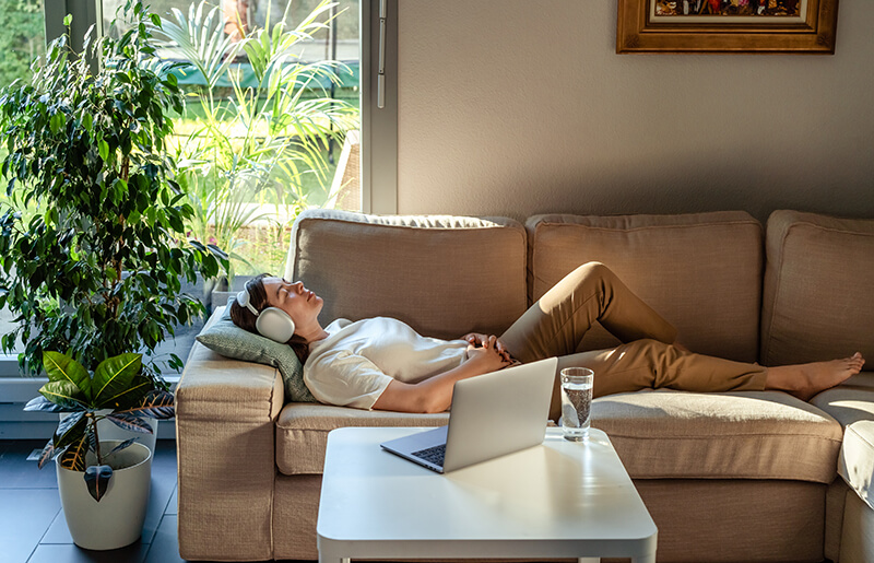 A photo of a young woman having online hypnotherapy regression session with psychotherapist lying on a sofa