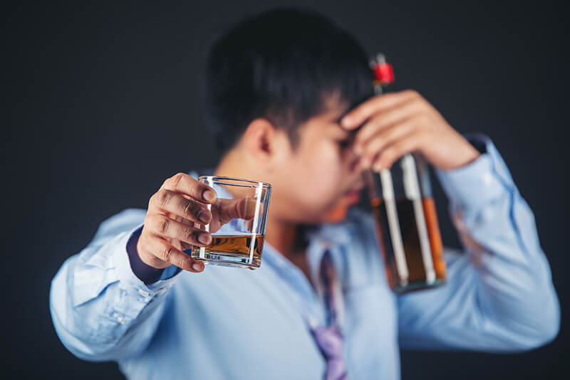 A photo of an alcoholic Asian man drinking whisky