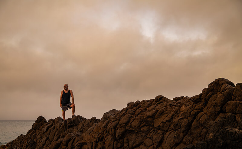 Photo of a man standing on rocks against the sea