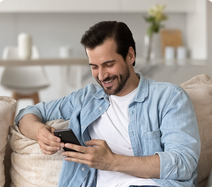 A photo of a man looking at his phone smiling