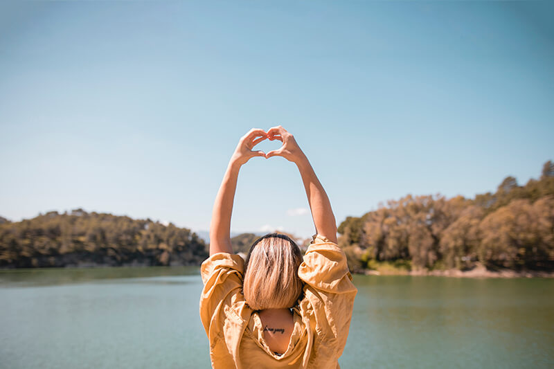 A photo of a woman showing the heart symbol with hands