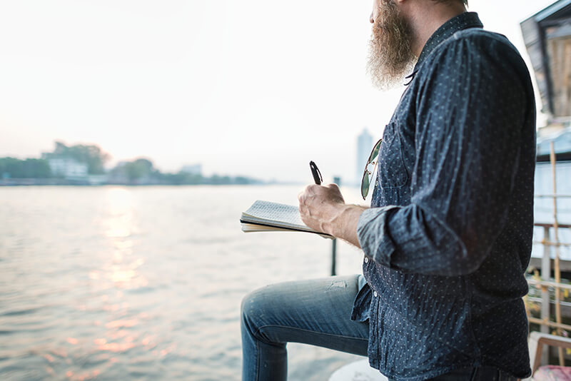 A photo of a man journaling by the lake