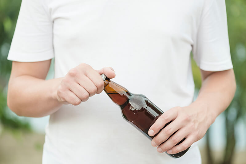 A photo of a man opening a beer bottle
