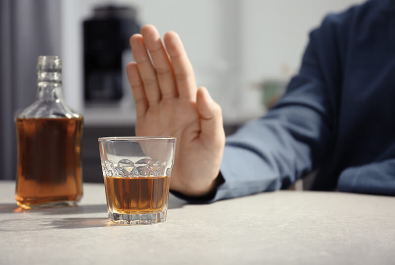 A photo of a man extending his hand out saying no to a poured drink