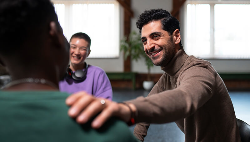 A photo of a man supporting another one in a group session