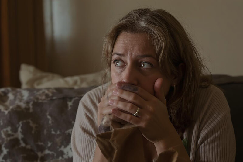 Photo of a woman looking troubled sitting on a sofa