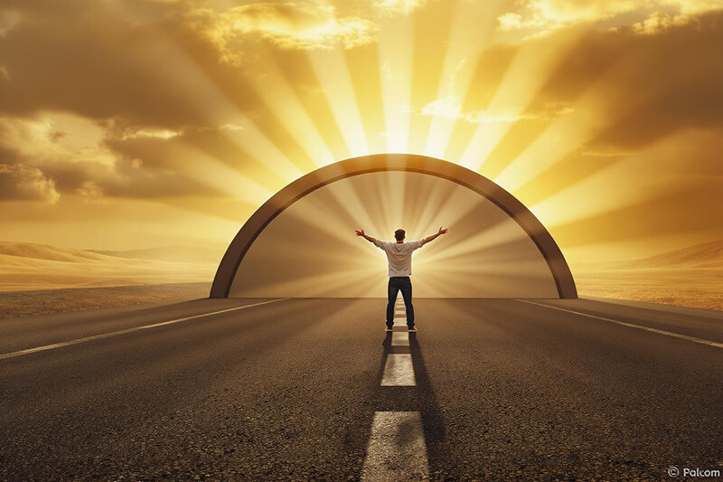 A photo of a man with his arms screeched out looking into a light