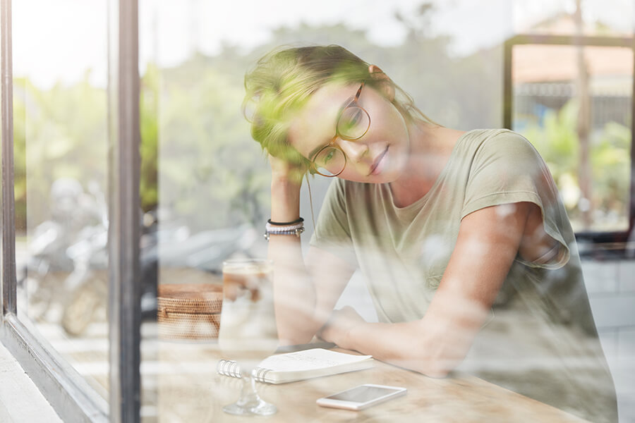 A photo of a woman in a glass reflection in a thinking posture
