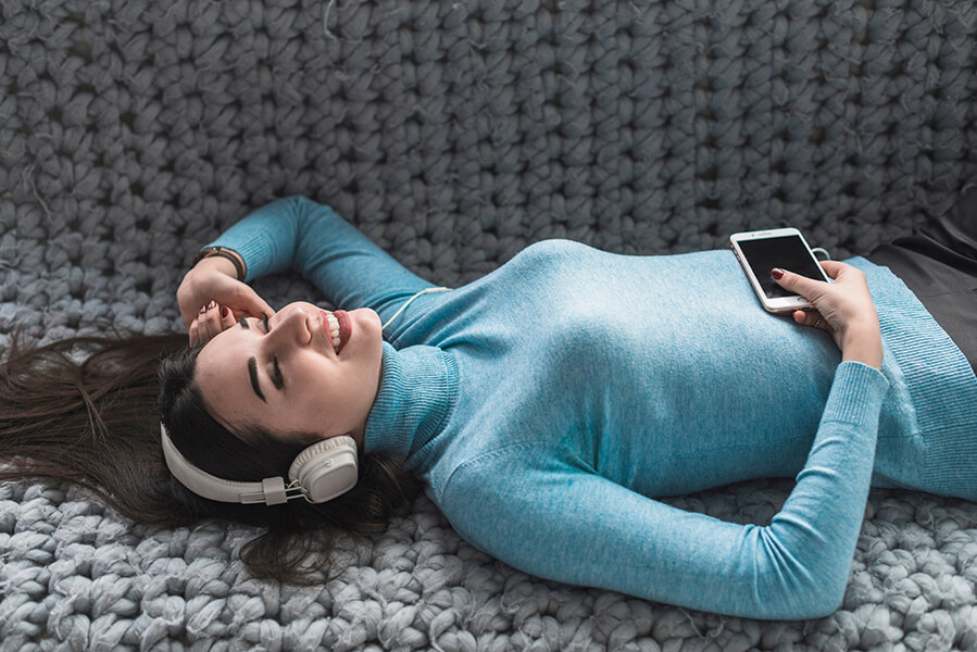 A photo of a woman lying down listening to headphones