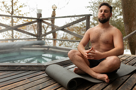 A photo of a man practicing yoga next to a pool