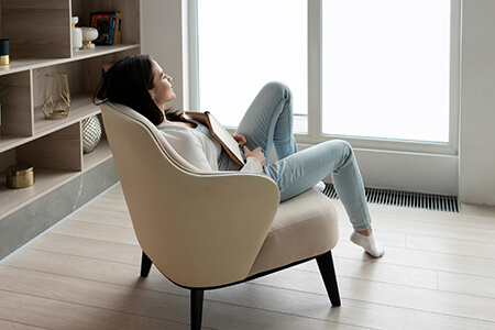 A photo of a woman sitting on a sofa with a book